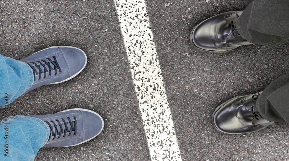 Mediation und Konfliktbegleitung durch dok-kommunikation: zwei Personen stehen sich gegenüber, es trennt sie eine Linie. Man sieht nur die Schuhe.